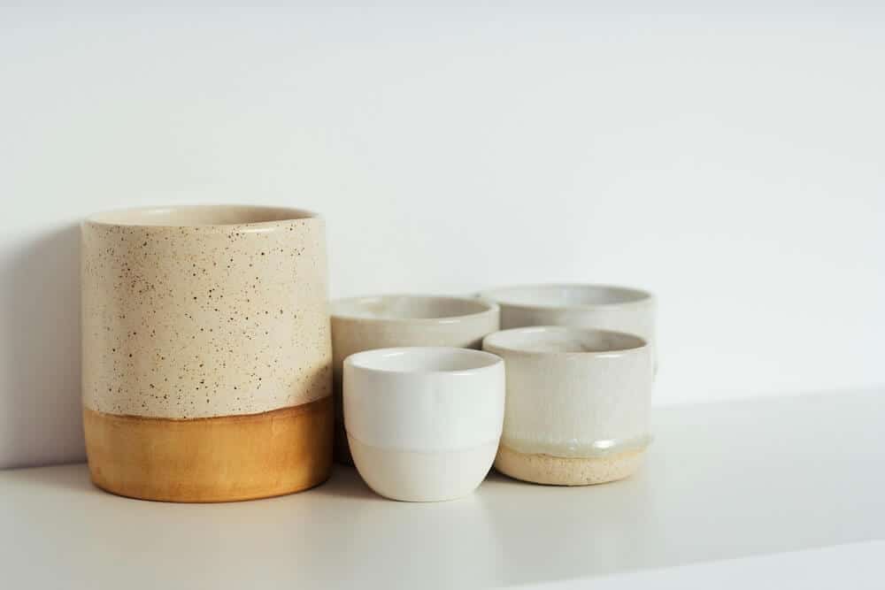Une tasse et quatre petits gobelets en céramique émaillés.